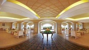 A spacious lobby with a patterned floor, a central round table, and seating areas on either side.