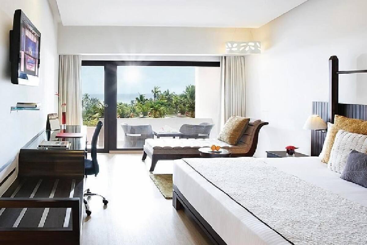 A hotel room with a large bed, a desk, a chair, and a view of the outdoors.
