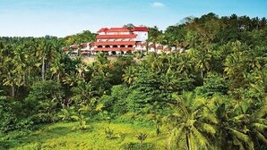 A multi-story building with a red roof, surrounded by dense tropical vegetation.