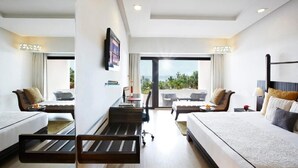 A hotel room with two beds, a desk, a chair, and a balcony with a view.