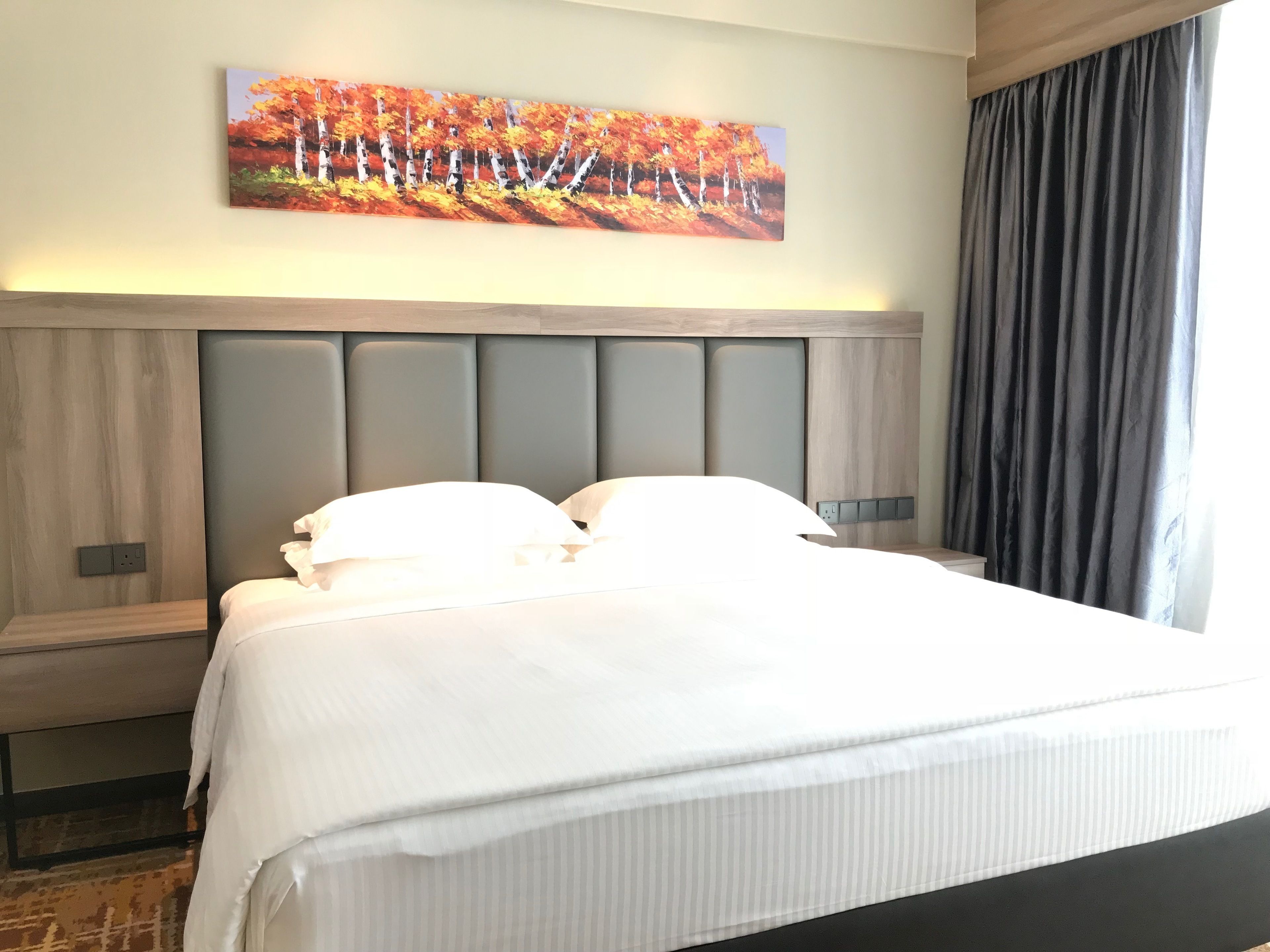 A neatly made bed with white linens in a hotel room.