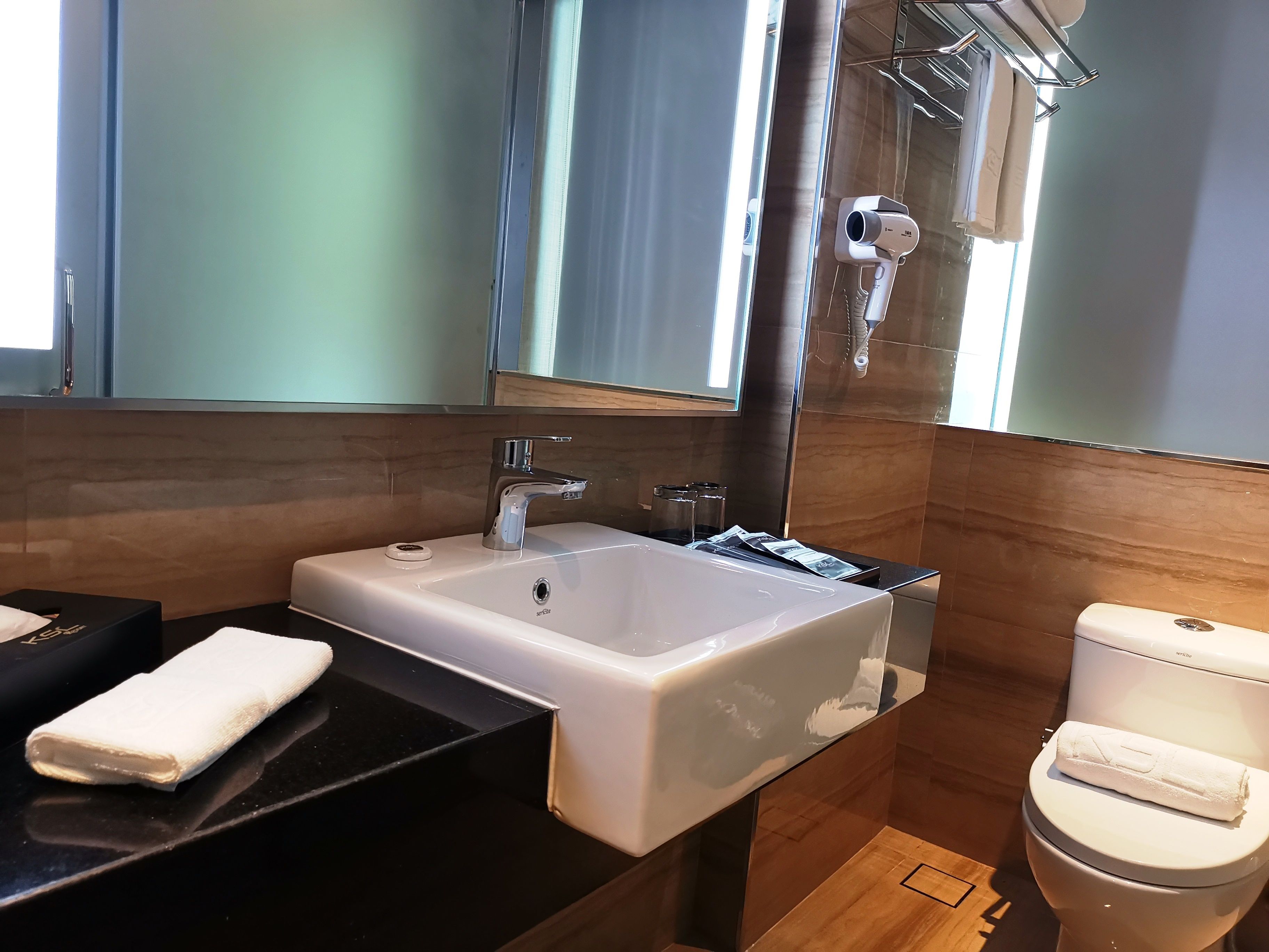 Un baño moderno con un lavamanos grande y blanco, un espejo encima y un inodoro con una toalla.