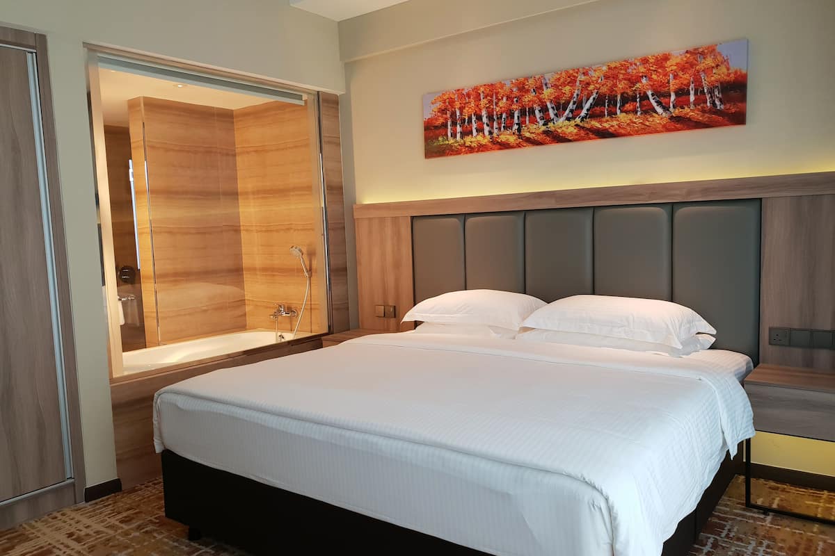 A hotel room with a large bed, a walk-in closet, a painting of autumn leaves, and a modern headboard.