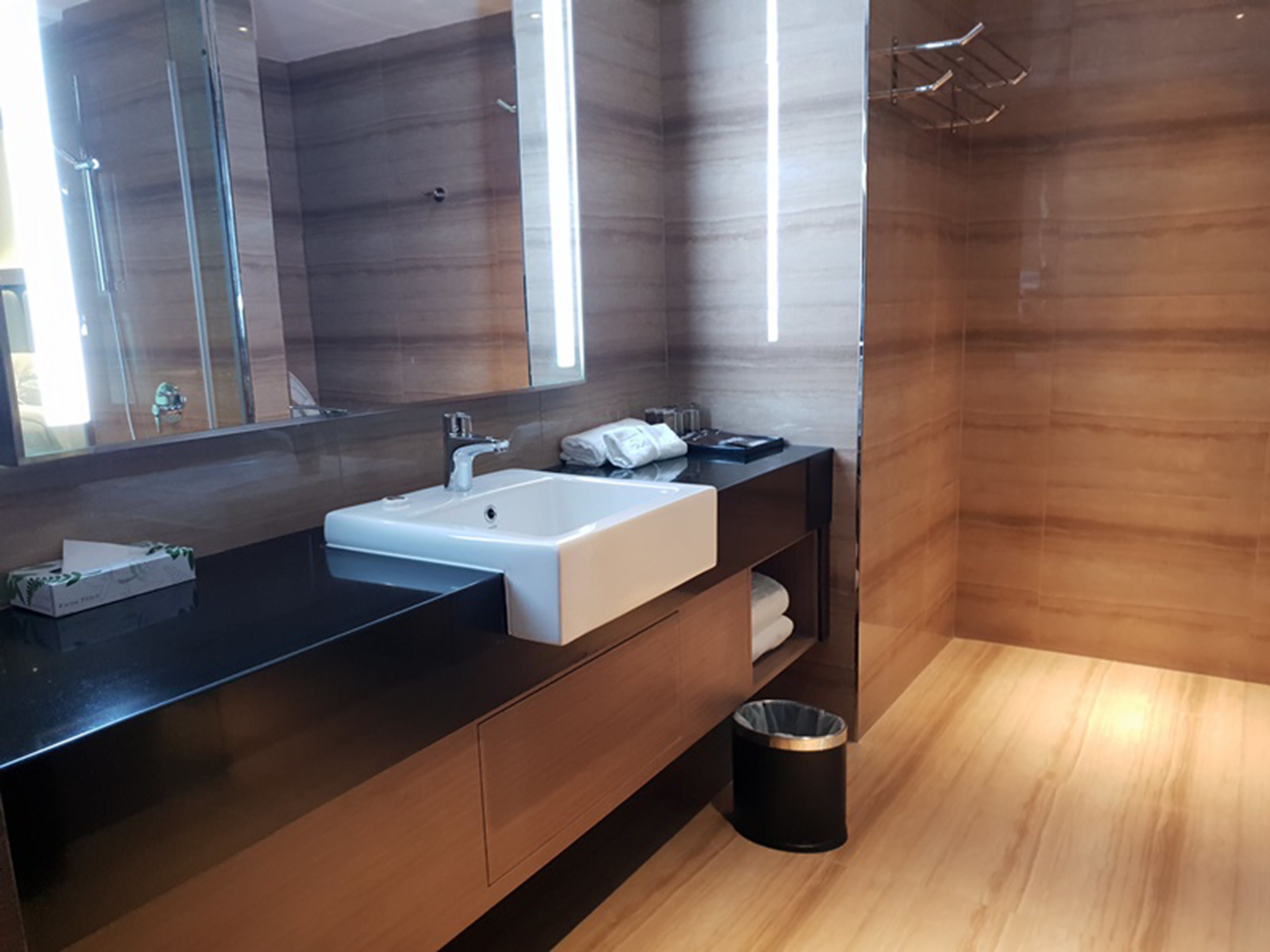 A modern bathroom with a large mirror, a white sink, and a black vanity.