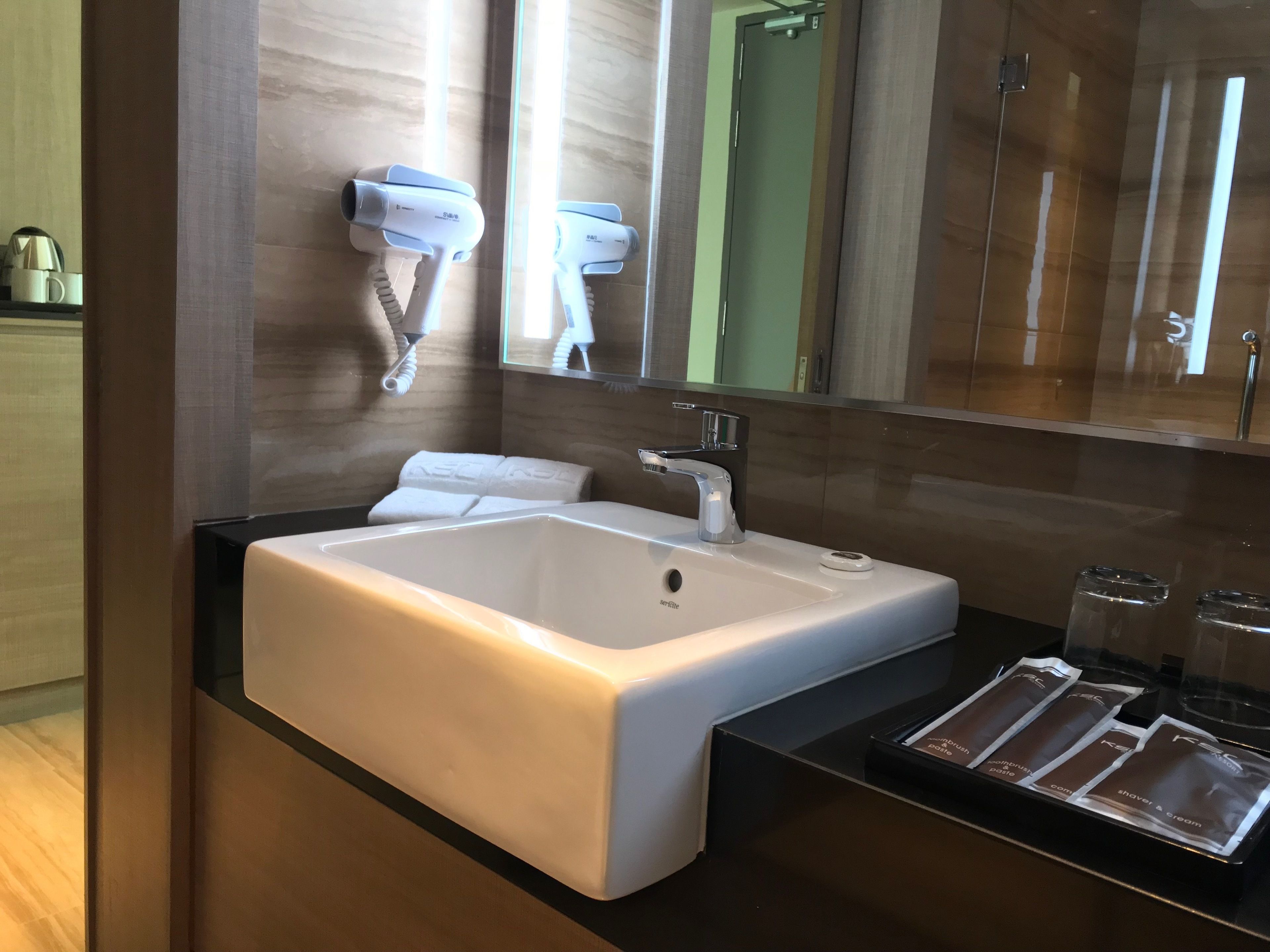 A modern bathroom with a white sink, a mirror, and a towel rack.