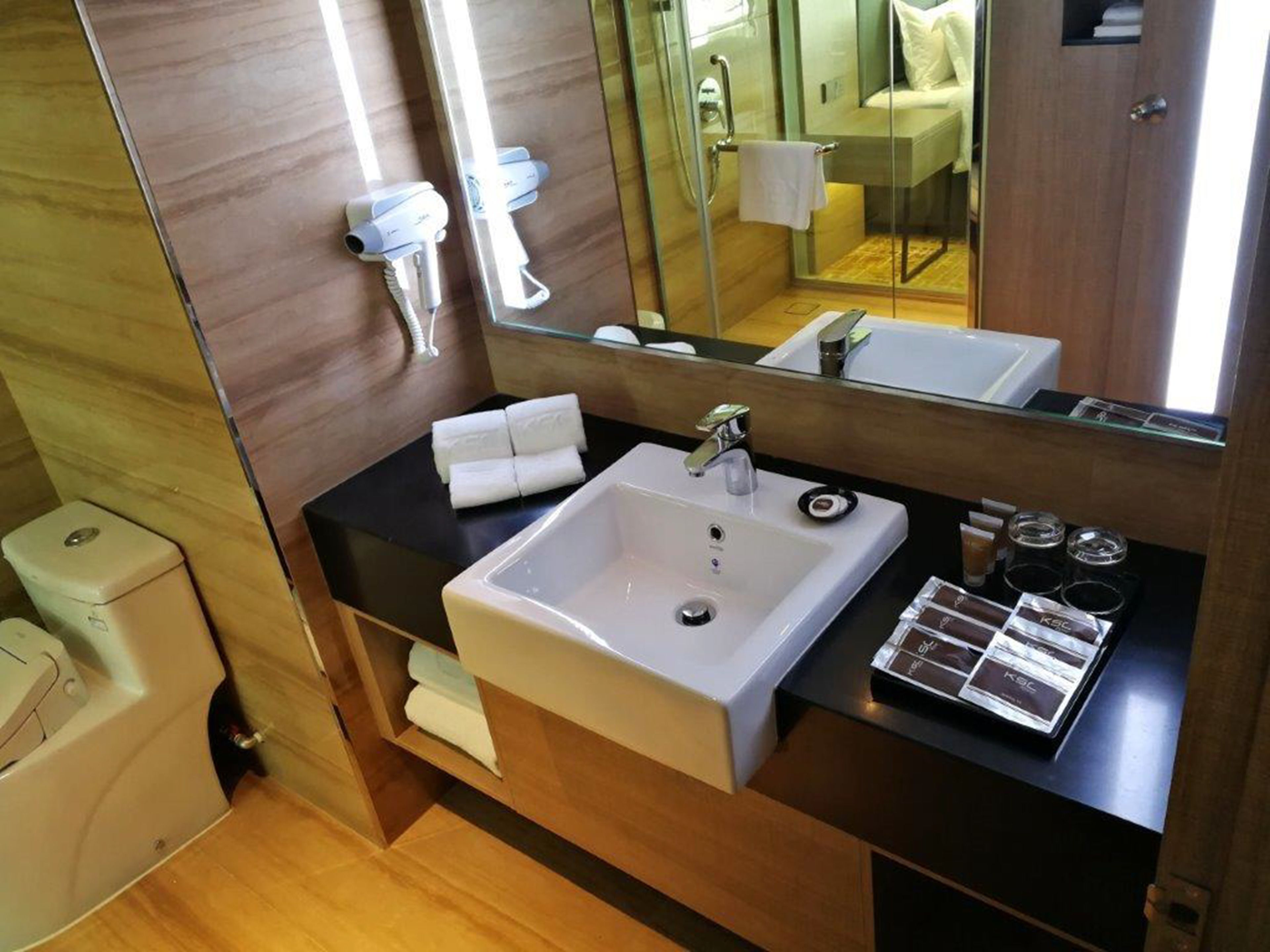 A modern bathroom with a large sink, a mirror, and a towel rack.
