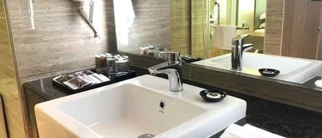 A modern bathroom with a large white sink, a mirror, and a black countertop.
