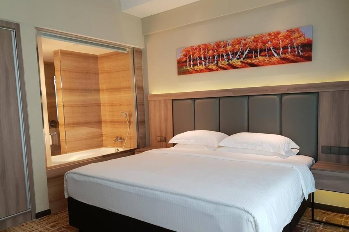A hotel room with a large bed, a walk-in closet, a shower, and a painting on the wall.