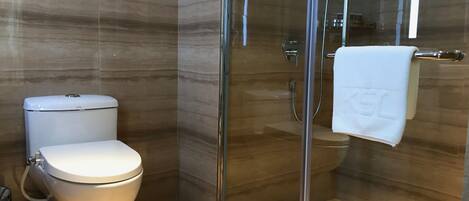 A modern bathroom with a toilet, a glass-enclosed shower, and a towel hanging on a rack.
