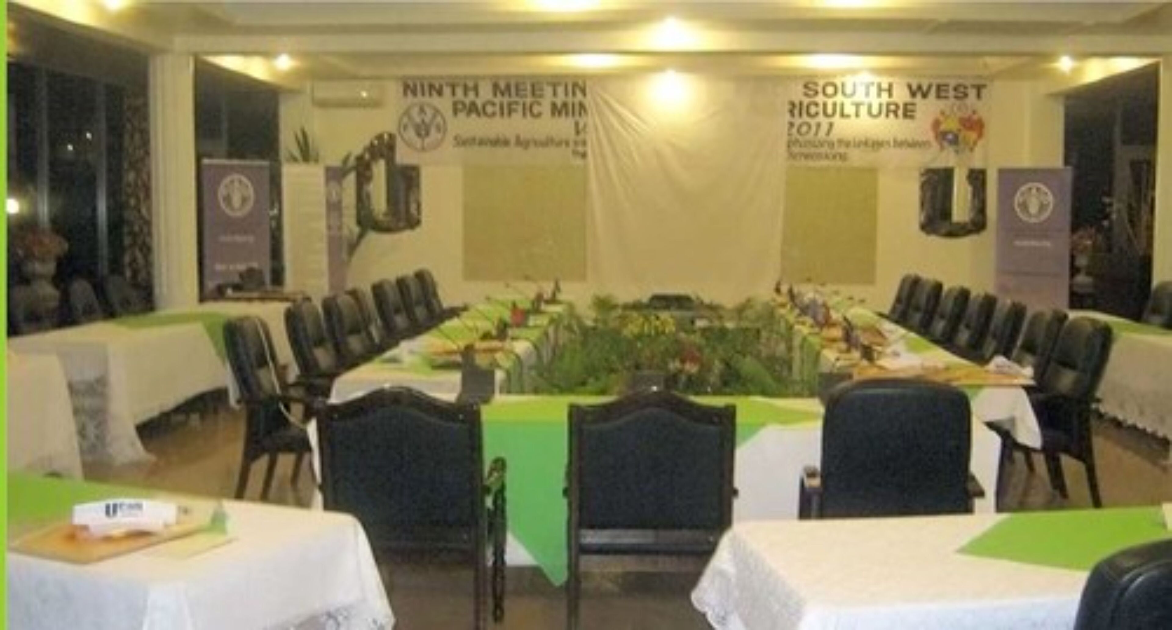 Un salón de conferencias con una larga mesa, sillas y pancartas para la Novena Reunión del Pacífico Norte y Agricultura del Suroeste 2011.
