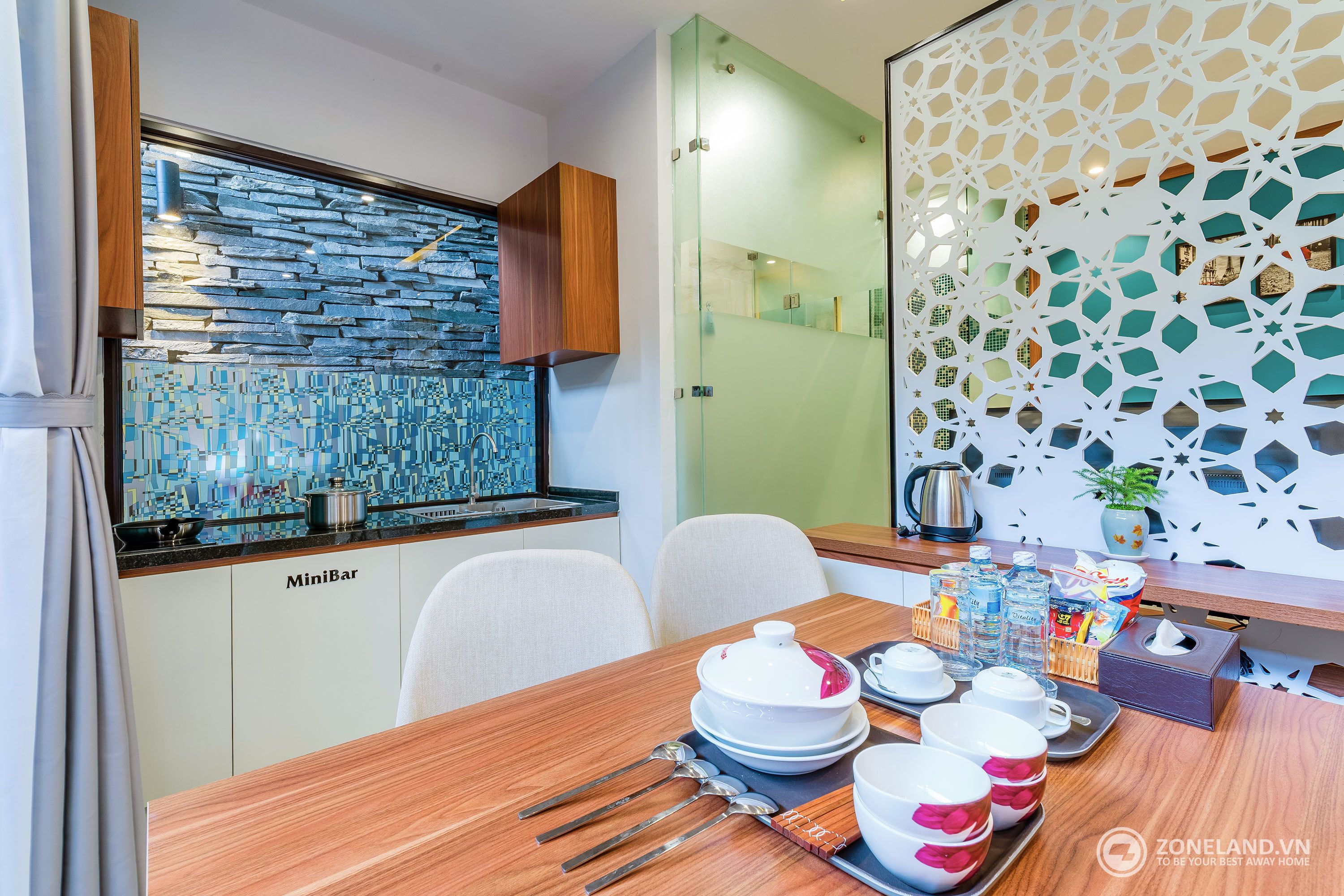 A compact kitchen with a stone backsplash, a MiniBar, and a dining area with a tray of dishes and utensils.