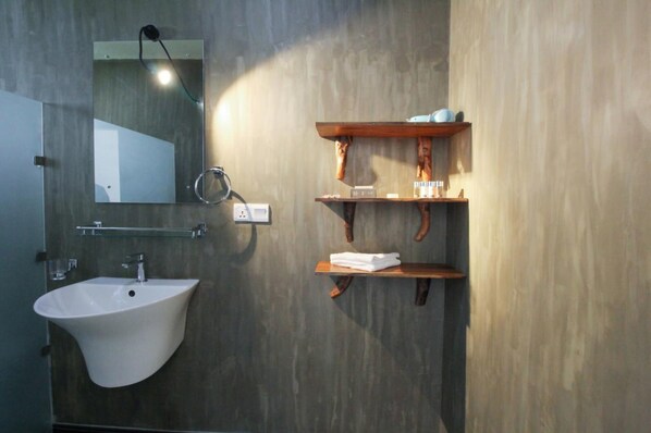 A bathroom with a white sink, a mirror, and wooden shelves with toiletries.