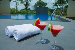 A poolside setting with two martini glasses and a rolled towel.
