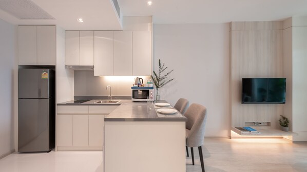 Una cocina moderna con microondas integrado, refrigerador y comedor con mesa y sillas.