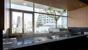 A modern spa with a large window, a hot tub, and a view of the cityscape. - Jasmine 59 Hotel Thonglor Bangkok (Bangkok)