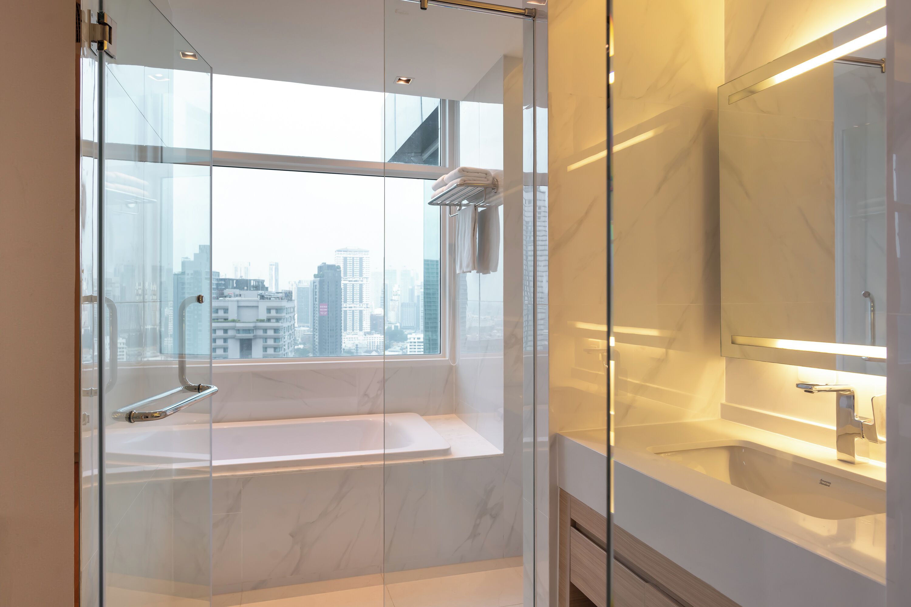 A modern bathroom with a glass-enclosed shower, a bathtub, and a large mirror.