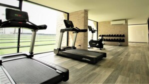 A gym with treadmills, a stationary bike, and a wall of dumbbells. - Phurinda Residence (Nong Khae)