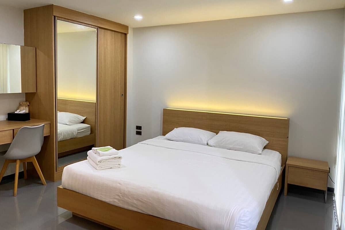 Una habitación de hotel moderna con una cama grande, un escritorio y un armario.