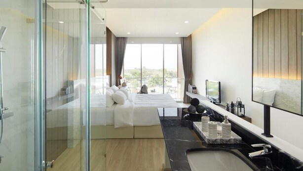 A modern hotel room with a large bed, a glass shower enclosure, a marble bathroom, and a city view. - Phurinda Residence (Nong Khae)