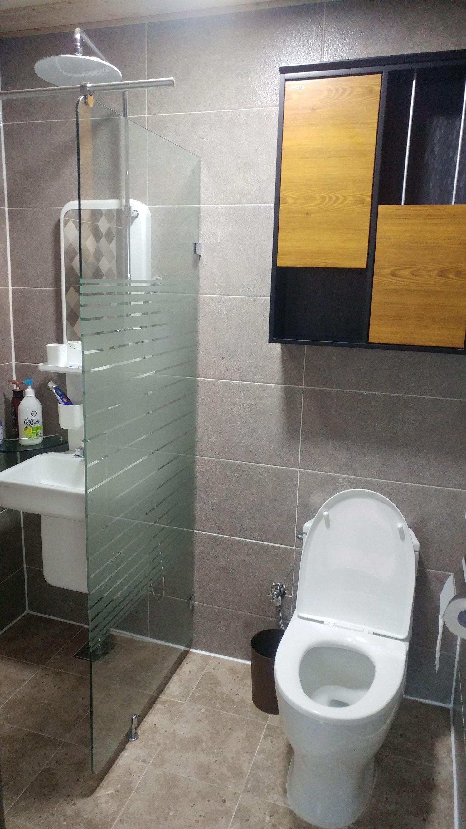 A bathroom with a glass shower enclosure, a toilet, and a sink.