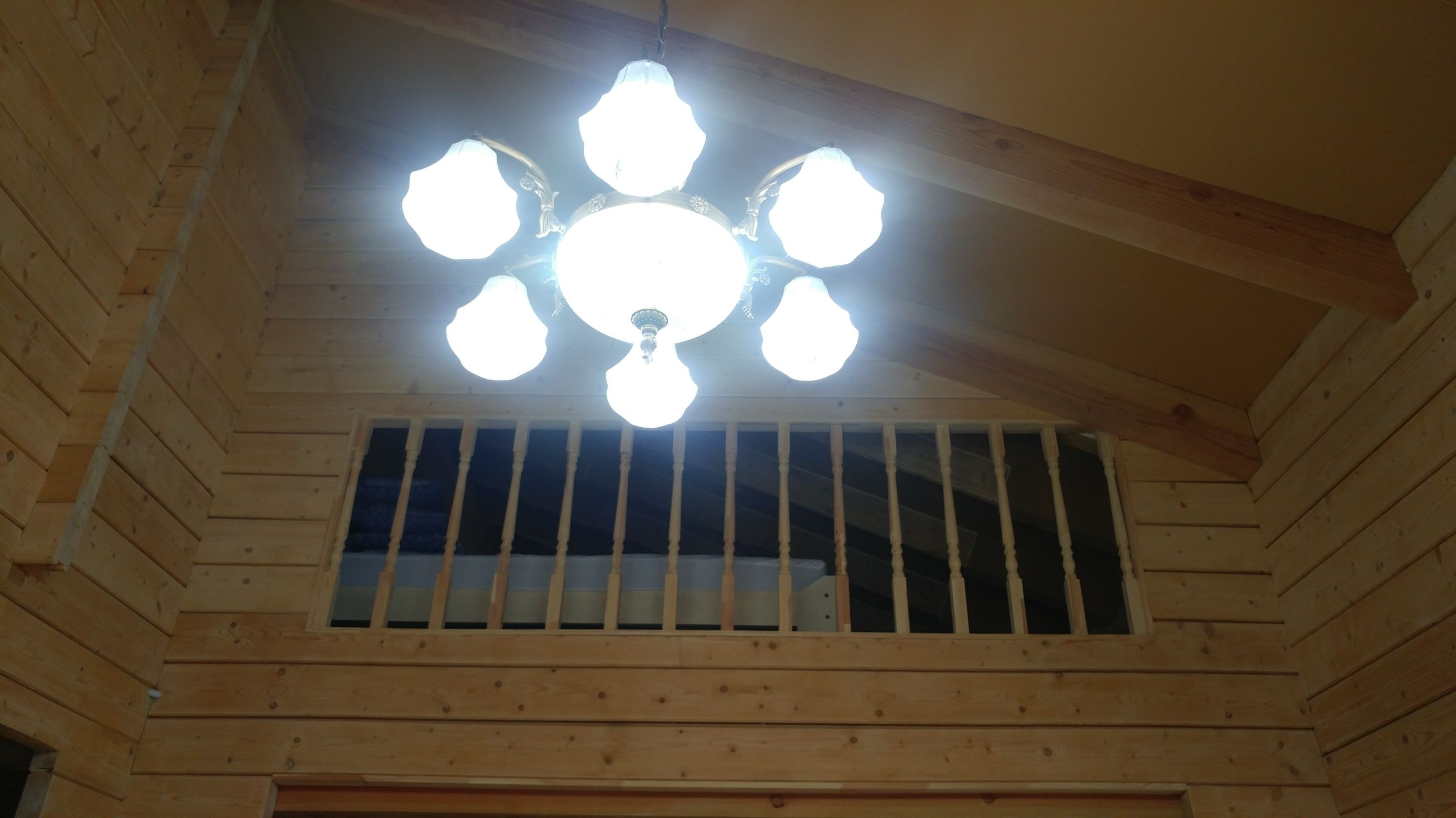 Un plafond en bois avec un luminaire central et une fenêtre grillagée en dessous.