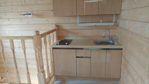 Eine Holzhütte mit einer Küchenzeile, einschließlich Spüle, Arbeitsplatte und Holzschränken.
