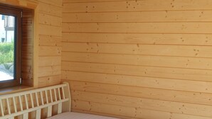 Ein Zimmer in einer Holzhütte mit einem Bett, einem Fenster und einer Deckenleuchte.