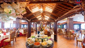 Un restaurante con una mesa de buffet central, techo de madera y decoración tradicional.