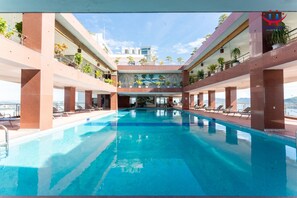 A swimming pool with a view of a building in the background. - Huong Viet Hotel Quy Nhon - Beachfront (Quy Nhon)