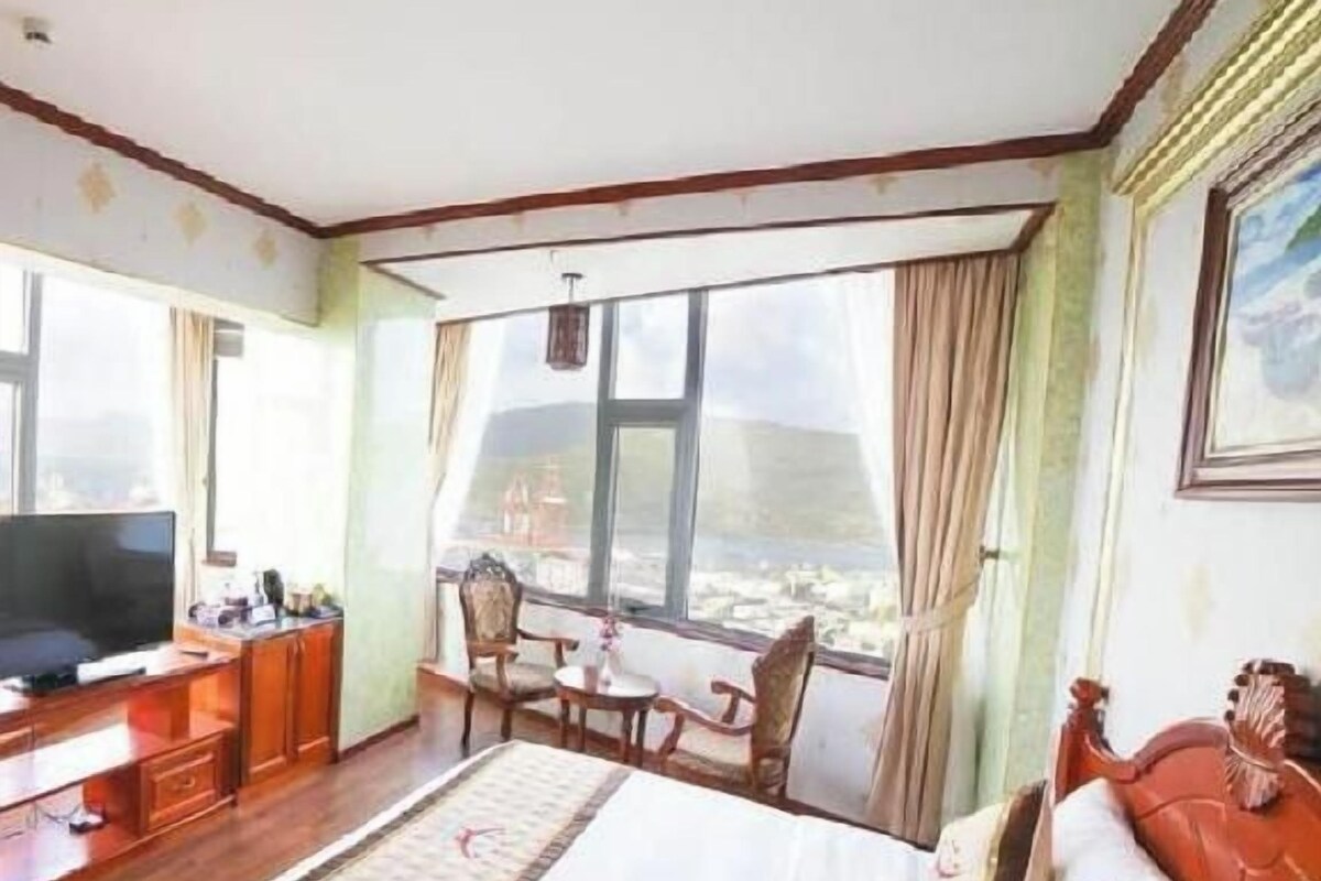 A hotel room with a bed, a desk, a television, and a window with a view.