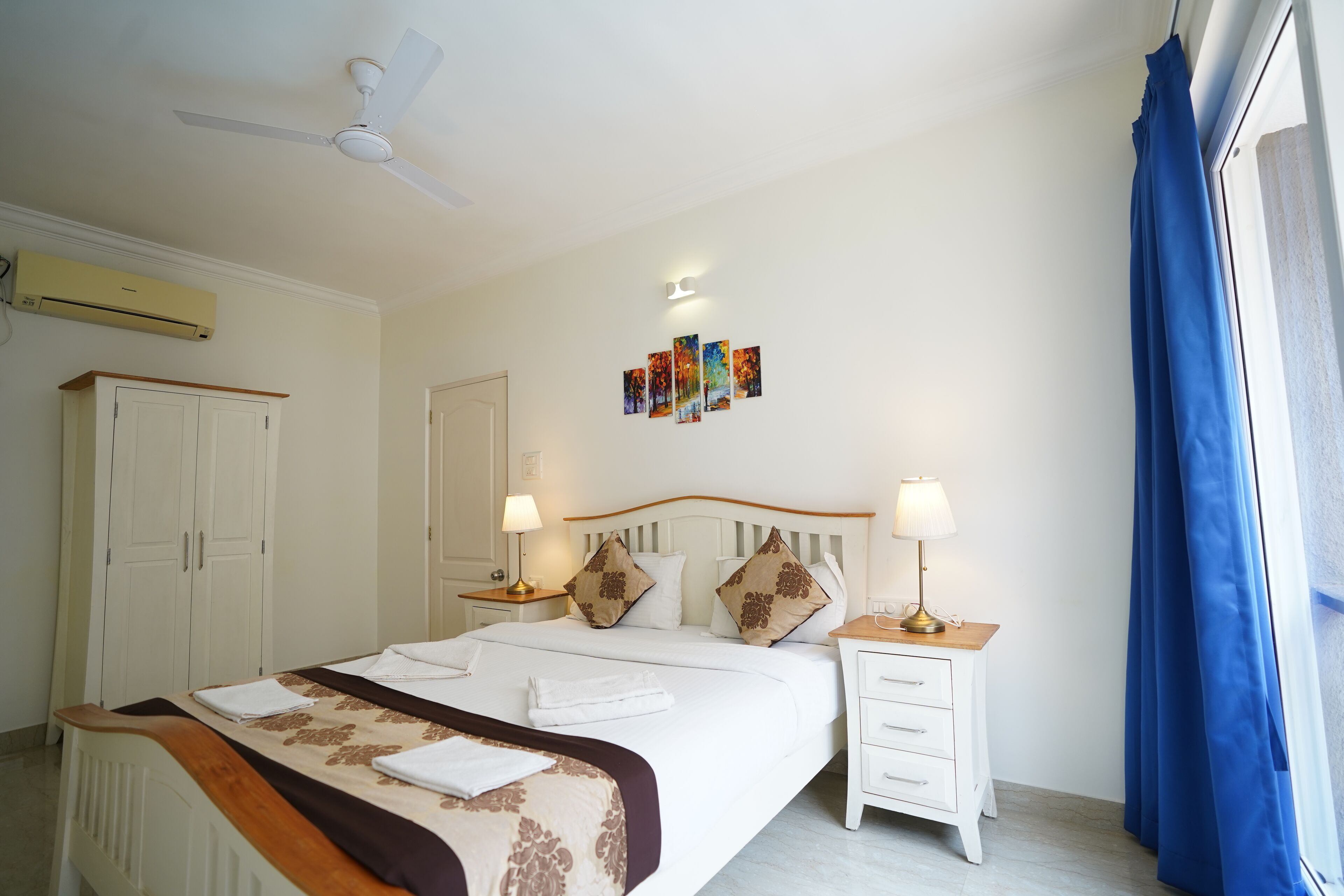 A neatly arranged bedroom with a bed, bedside tables, a ceiling fan, and a window with curtains.