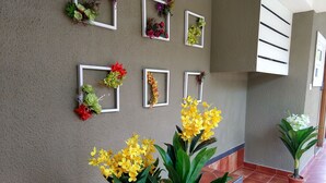 Un pasillo con pared texturizada, plantas en macetas y cuadros decorativos con motivos florales.