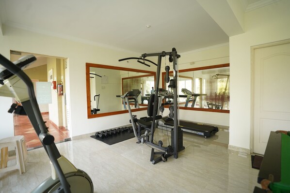 Un gimnasio con equipo de ejercicio, cinta de correr y un espejo grande.