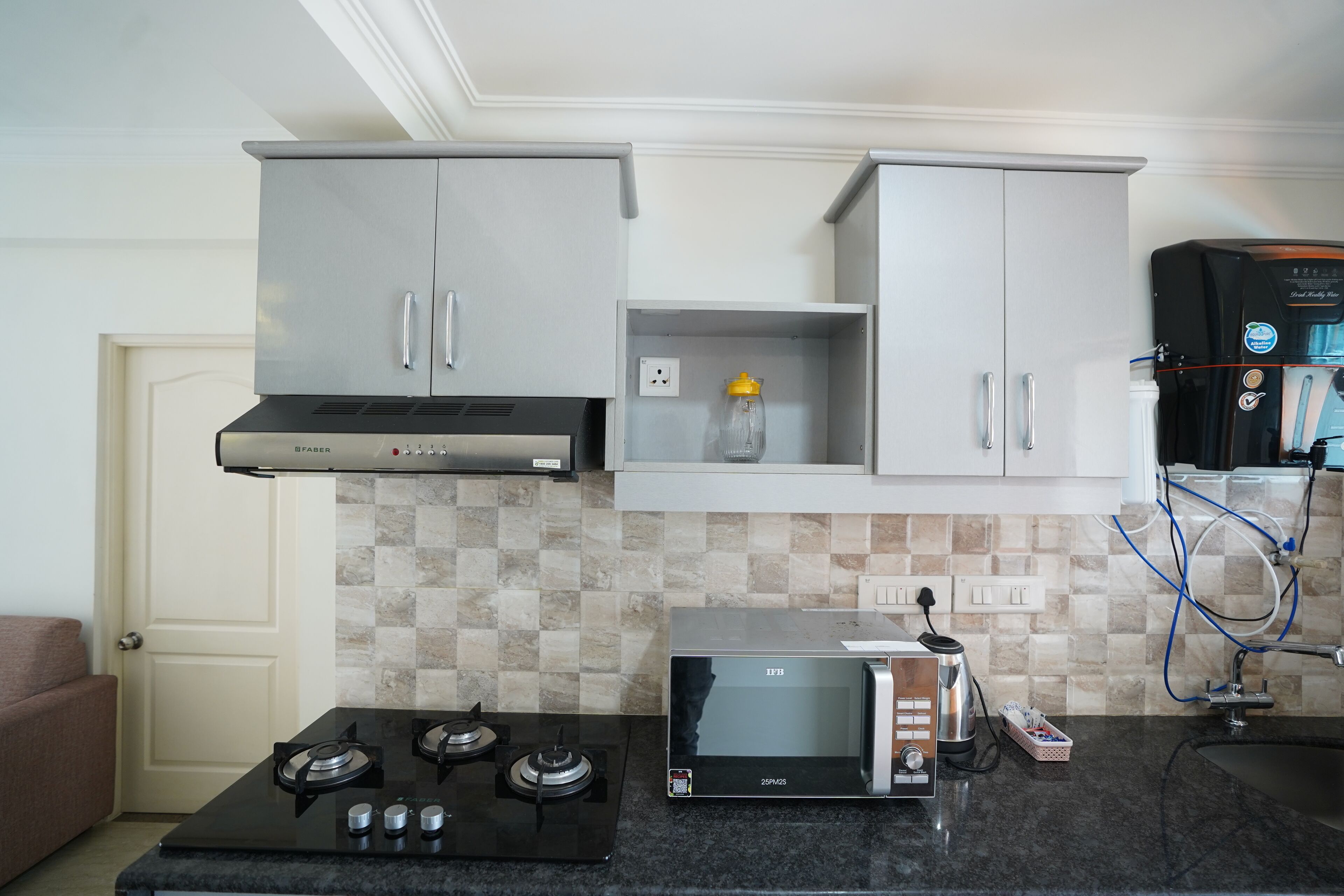 A kitchen with a gas stove, microwave, and a water dispenser.