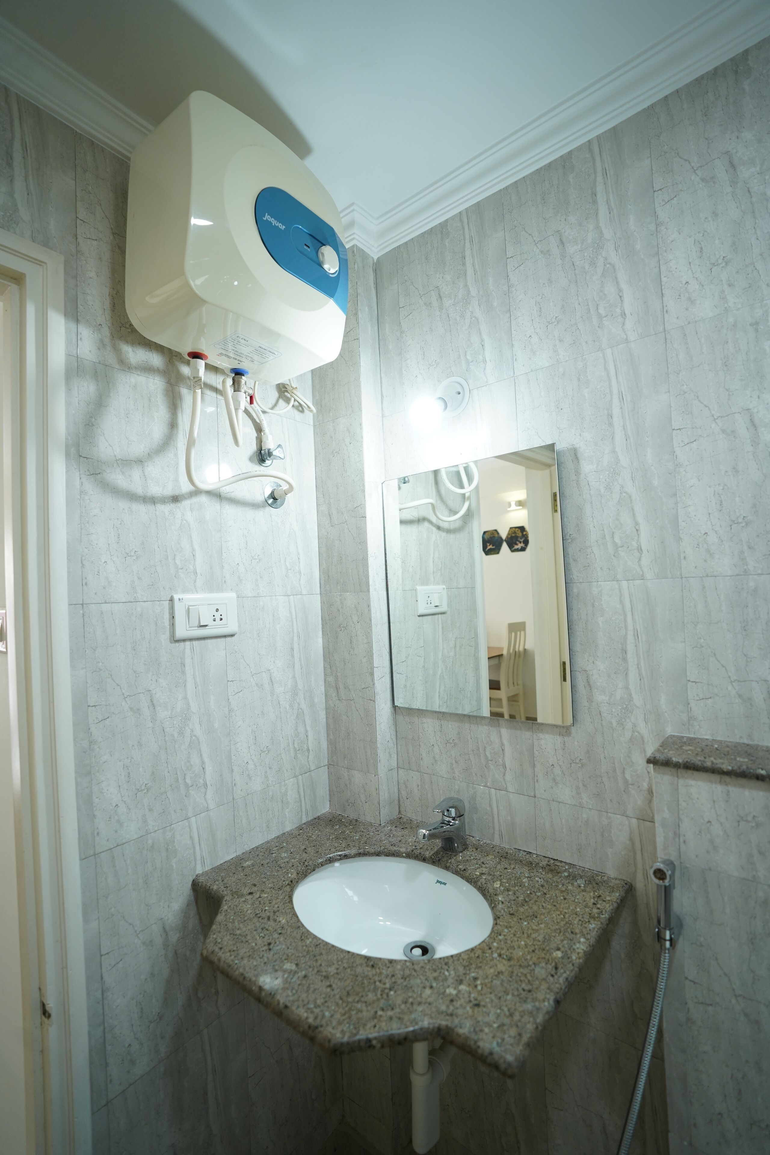 Une salle de bain avec un lavabo en granit, un miroir et un chauffe-eau fixé au mur.