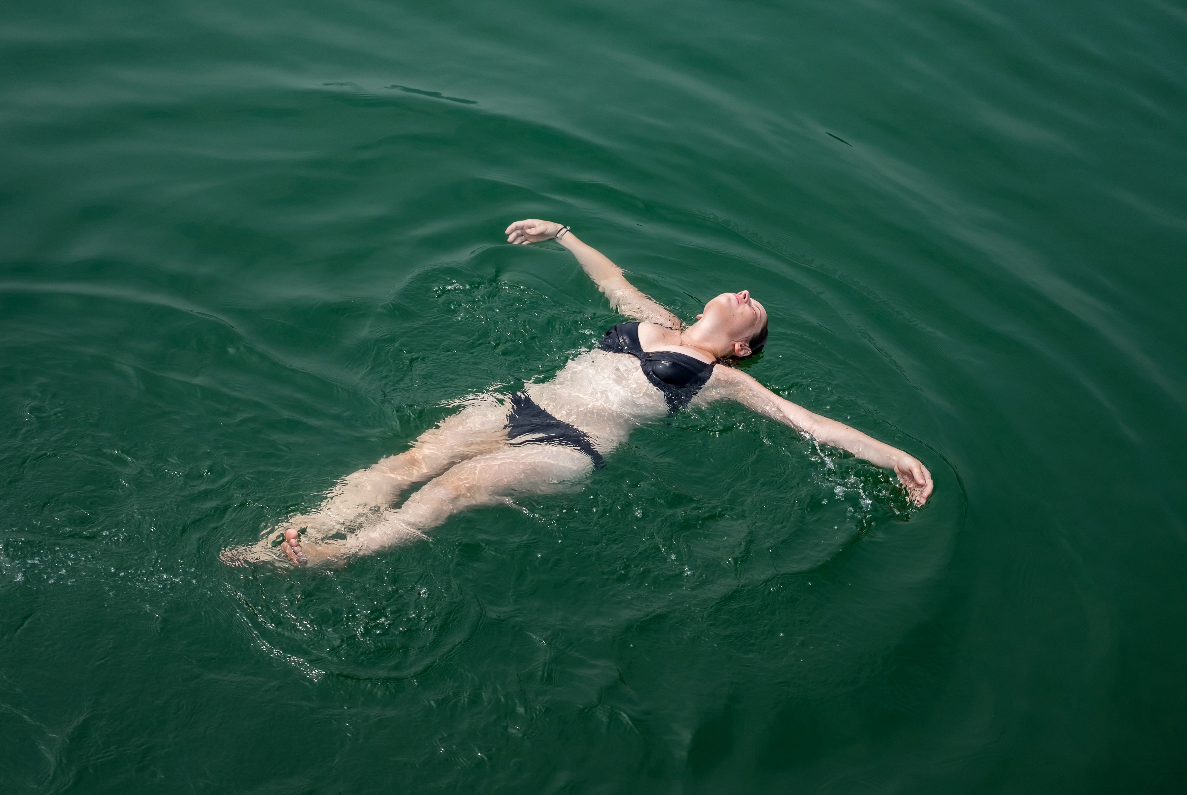 Iemand drijft op het water in een zwempak.