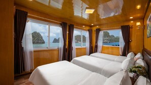 A cabin with two beds, wooden walls, large windows, and a view of the sea. - Azela Cruise (Hai Phong)