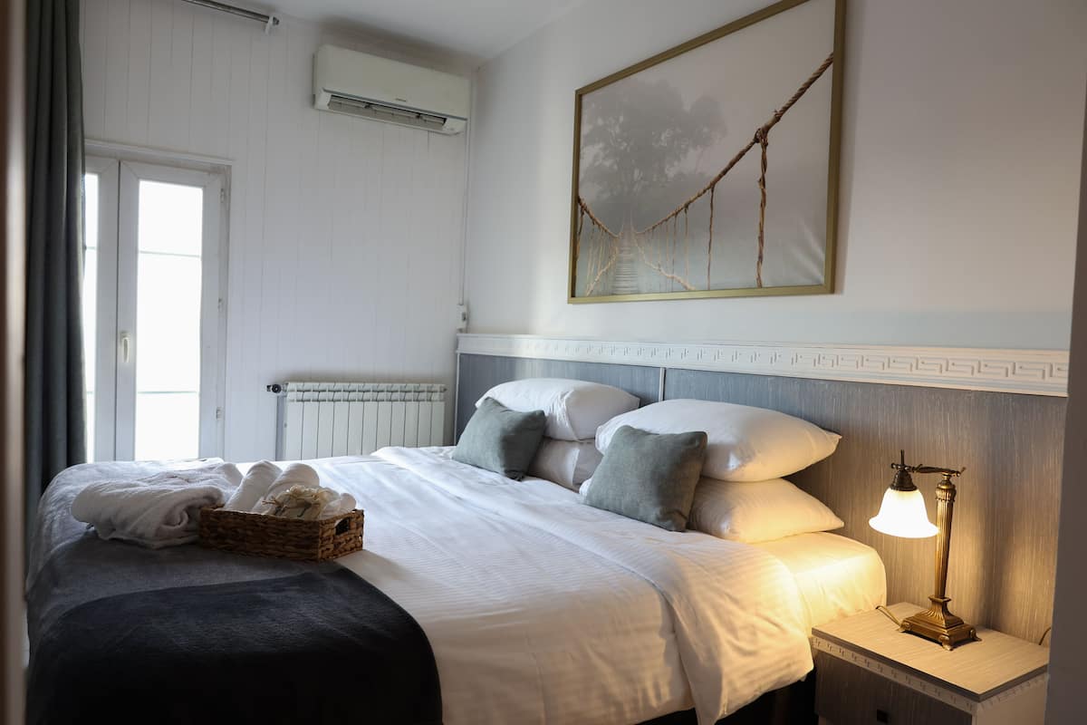 Un lit bien fait, avec des oreillers et une table de chevet sur laquelle se trouve une lampe.