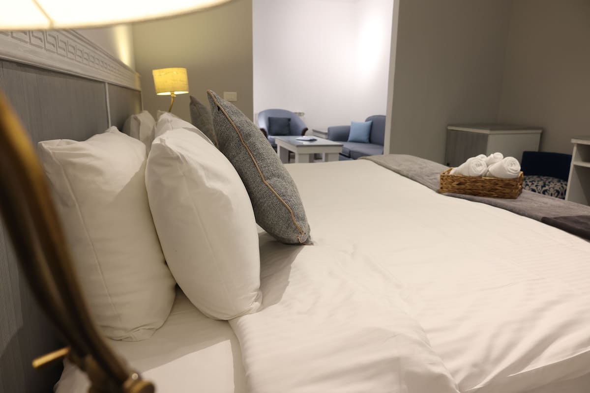 Un lit bien fait, avec du linge de lit blanc et un panier rempli de serviettes.