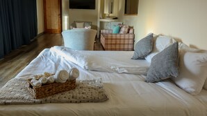 Una habitación de hotel con una cama grande, una zona de estar con una silla y un sofá, un televisor y una puerta de madera.