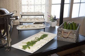 A buffet table with various food items, including a tray of cheese and a wooden crate of cucumbers.