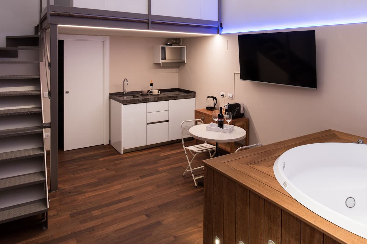 Une cuisine moderne dotée d’une cuisinière intégrée, un coin repas avec une table et des chaises, et une grande baignoire.