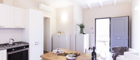 A modern kitchen with white cabinets, a wooden dining table, and a view of the outside.