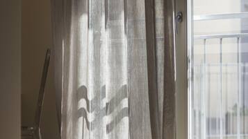 A room with a large window, a chair, and a curtain.