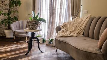 Una sala de estar acogedora con un sofá color beige, una mesa redonda con una planta en maceta y un sillón.