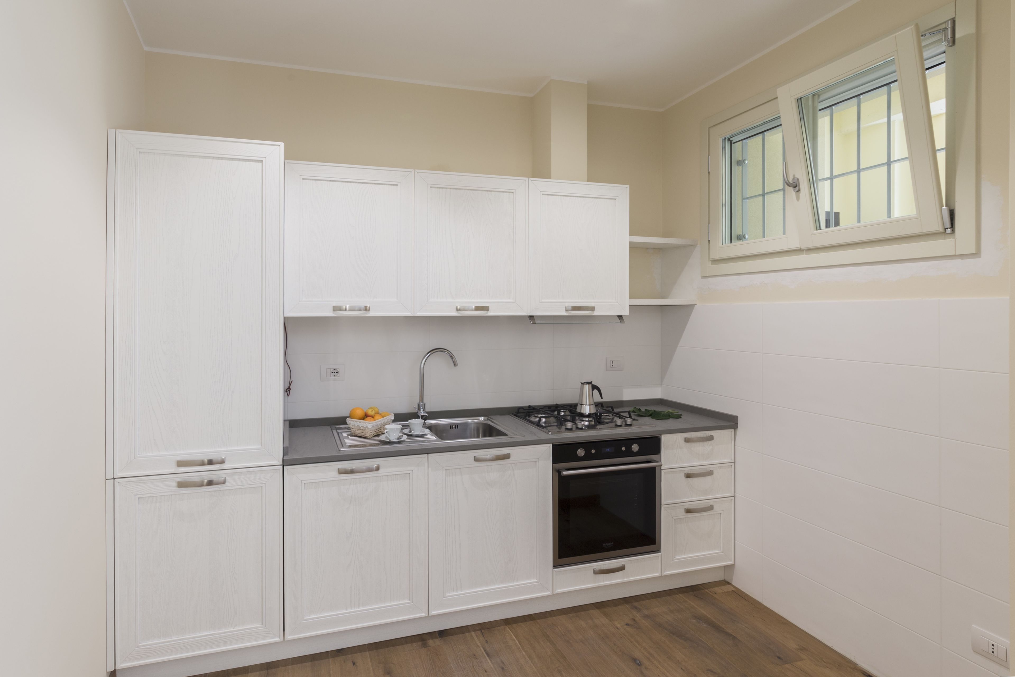 A compact kitchen with white cabinetry, a gas stove, and a built-in oven.