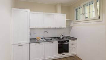 A compact kitchen with white cabinetry, a gas stove, and a built-in oven.