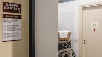 A laundry room with a washing machine, a basket with a towel, and a door with a 'no entry' sign.