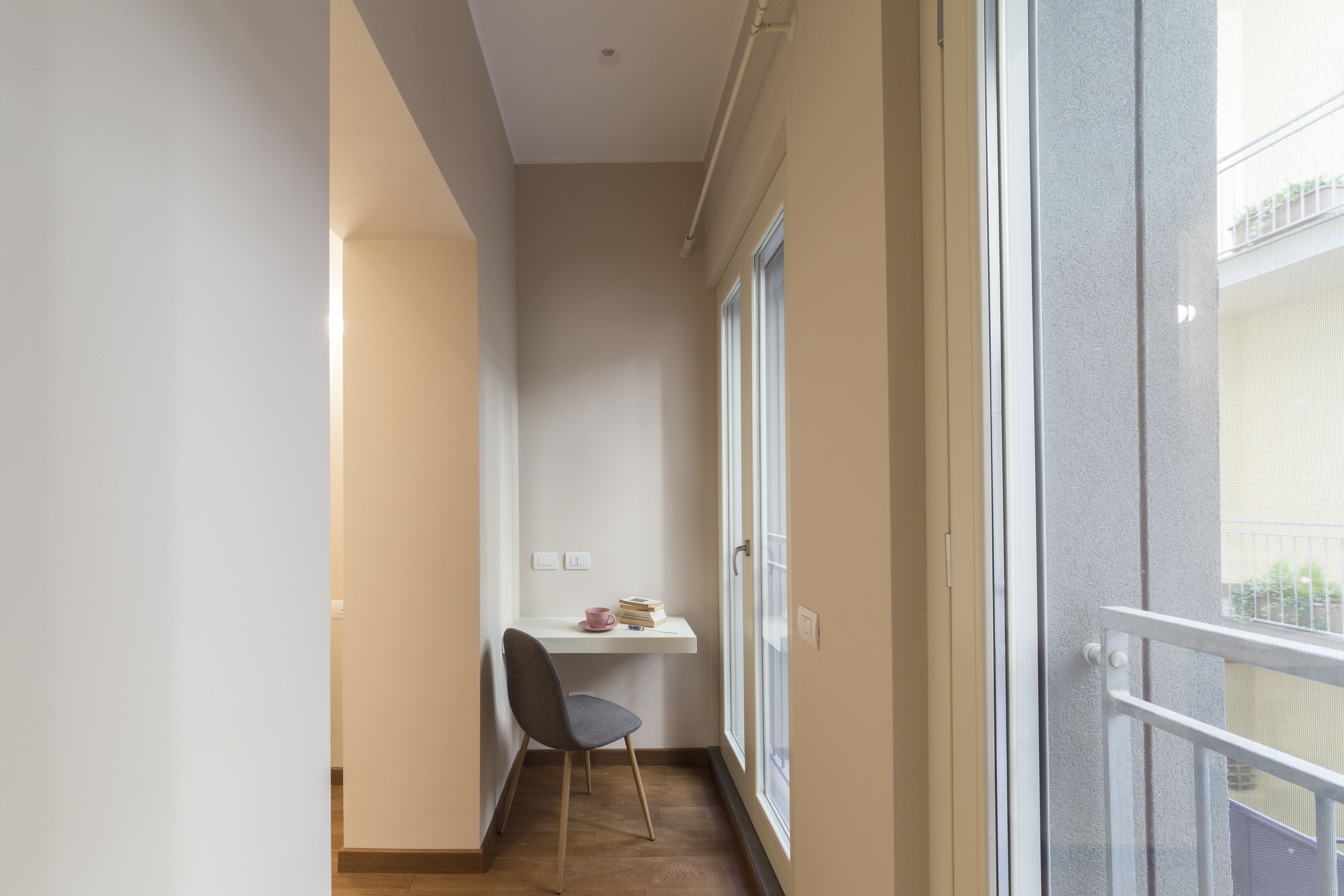 A narrow balcony with a chair, a small table, and a window.