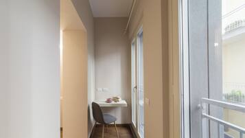 A narrow balcony with a chair, a small table, and a window.